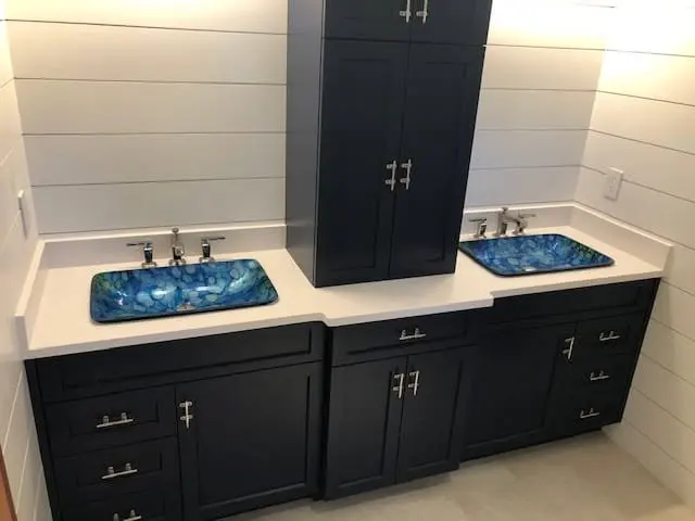 Double bathroom vanity with white stone countertops and blue glass vessel sinks.