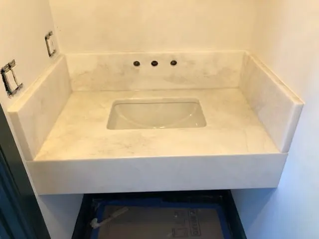 White stone bathroom vanity with an integrated sink.