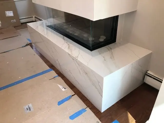 Veined stone fireplace surround in a completed room.