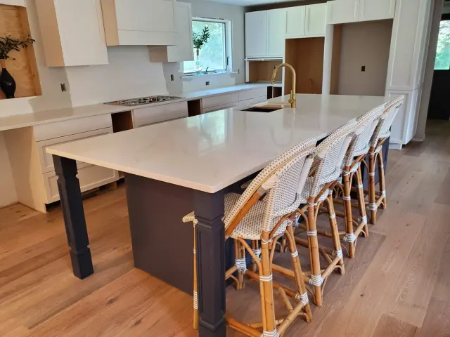 Large white stone island in an open kitchen.