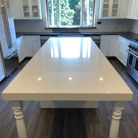 White stone counters and island in a finished kitchen.