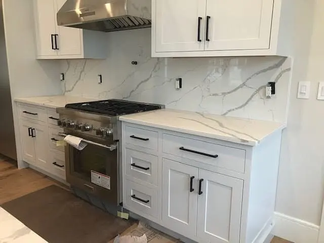 White stone countertops around a kitchen range.