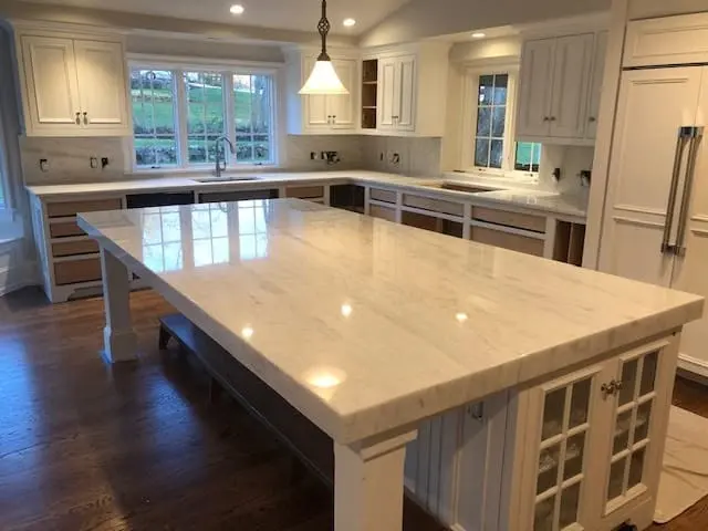 Large white stone island in a bright completed kitchen.