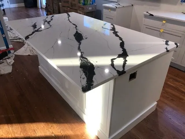 White waterfall kitchen island with bold black veining.