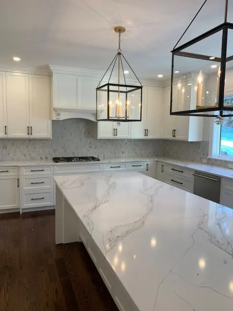 White stone island and countertop in a completed kitchen.