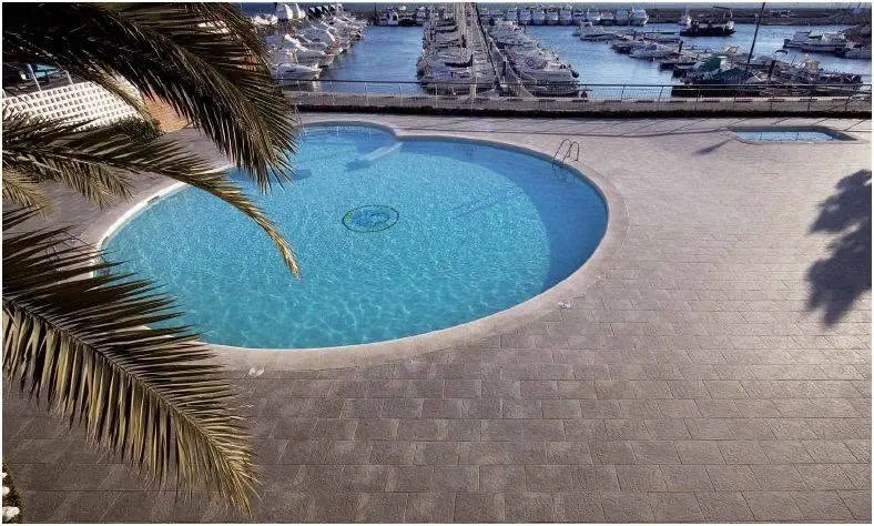 Outdoor tile and paver surface beside a pool.