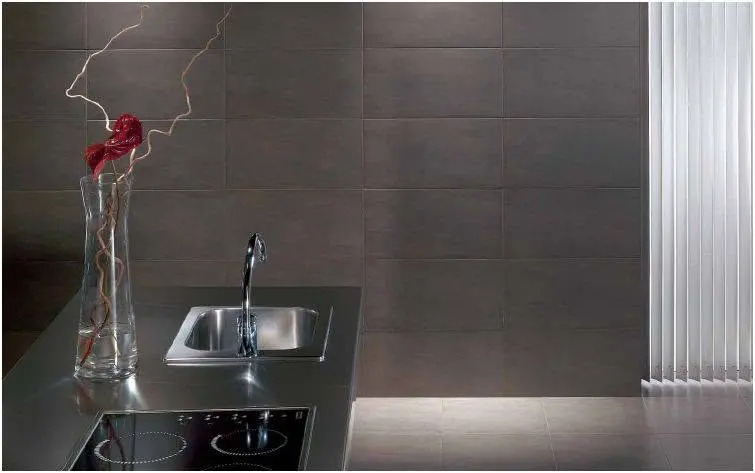 Dark tile backsplash behind a kitchen sink.