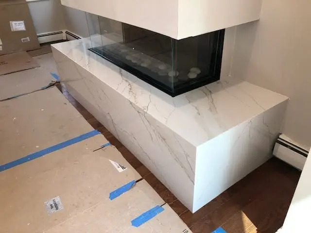 Veined stone fireplace surround in a completed room.