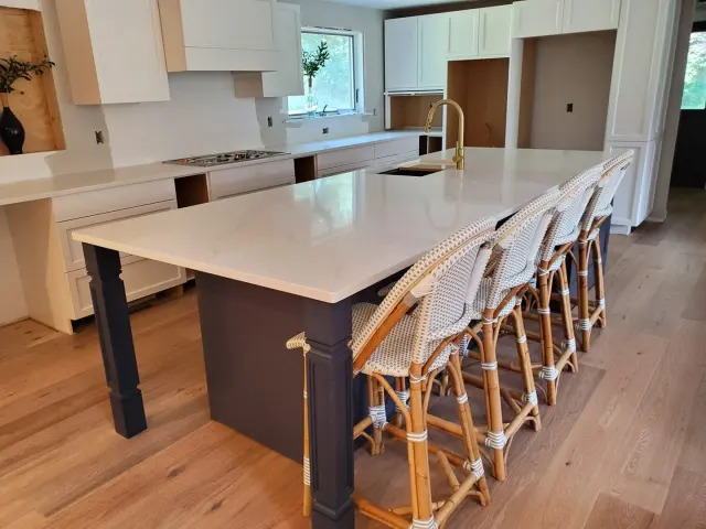 Large white stone island in an open kitchen.